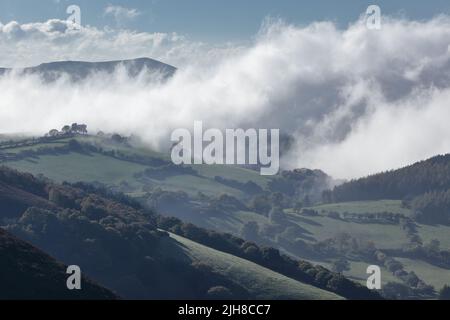 Una vista aerea di Corndon Hill, Galles, e Shropshire Valley con nebbia crescente al mattino presto. Foto Stock