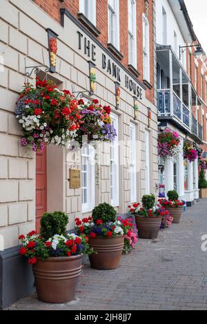 Cestini appesi e vasi di fiori fuori dalla Bank House nella città di Pershore, Worcestershire, Regno Unito Foto Stock