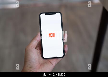 CHIANG mai, THAILANDIA, 12 LUGLIO 2022 : Donna mano tenere Apple iPhone X con App YouTube fornisce streaming di media e video sullo schermo. Foto Stock