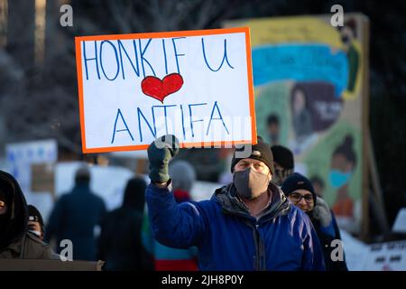 Un uomo ha un segno 'Honk se amate Antifaa' per una contro-protesta al convoglio della libertà a Ottawa, Canada. Febbraio 2022 Foto Stock