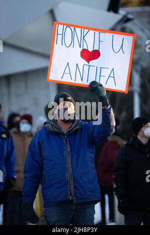 Un uomo ha un segno 'Honk se amate Antifaa' per una contro-protesta al convoglio della libertà a Ottawa, Canada. Febbraio 2022 Foto Stock