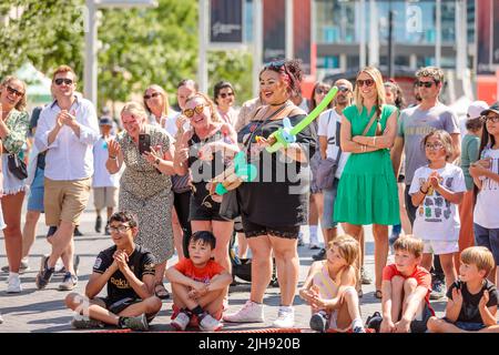 Wembley Park, Londra, Regno Unito. 16th luglio 2022. La folla si gode gli spettacoli al sole mentre il giorno dell'autobus internazionale ritorna al Wembley Park. Il festival gratuito di un giorno ha grandi nomi che condividono 9 palcoscenici insieme ad artisti e artisti emergenti e a grandi opere. L'evento del Wembley Park include anche aree per il divertimento di tutta la famiglia con laboratori di abilità circensi, spettacoli di magia e commedia, routine di escapologi, pittura facciale e artisti di palloncini. La Giornata Internazionale del Busking, sostenuta dal Sindaco di Londra, è presentata da Busk a Londra. Amanda Rose/Alamy Live News Foto Stock