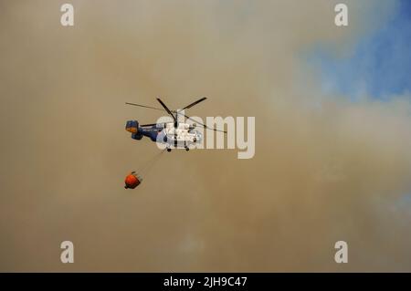 Elicottero pesante dell'INFOCA che trasporta un secchio d'acqua per cadere su un fuoco selvatico, Mijas, Spagna. Foto Stock