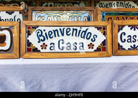 Benvenuto casa segno colorato scritto in spagnolo che dice 'bienvenidos a casa' in vendita in un mercato di strada a Los Sapos città magica a Puebla città, Messico Foto Stock
