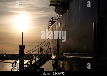 Silhouette di una nave da crociera e barca ormeggiata in mare lungo il porto di Bodo, Nordland, Norvegia al tramonto con spazio copia. Porto panoramico sul lungomare a Foto Stock