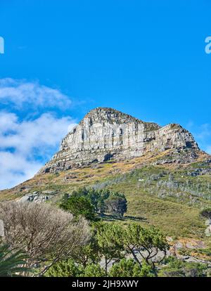 Paesaggio panoramico di cielo blu sopra la cima di Table Mountain a Città del Capo in una giornata di sole dal basso. Bella vista di piante e alberi intorno a. Foto Stock