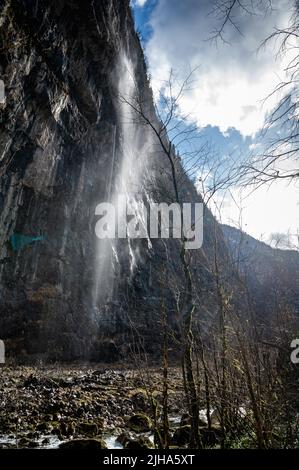 Cascata di montagna in Abkhazia. Il vento soffia via la pressione dell'acqua Foto Stock