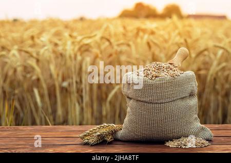 grani di grano in sacco di burlap su tavola all'aperto Foto Stock