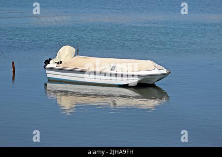 KANONI, CORFU, GRECIA - 13 SETTEMBRE 2017 barca da pesca ormeggiata ad un bastone con copertura in acqua blu ancora limpida con riflessi Foto Stock