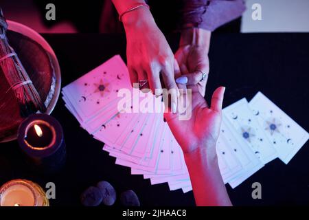 Fortune Teller che punta alla linea d'amore sulla palma del cliente femminile Foto Stock