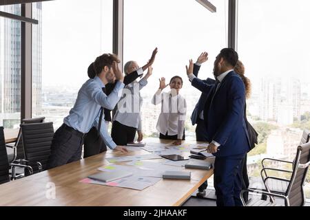 I colleghi d'affari sono entusiasti di dare cinque persone al tavolo di riunione Foto Stock