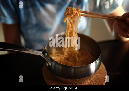 Mangiare spaghetti istantanei in pentola di alluminio Foto Stock