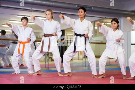 I bambini adolescenti che indossano le pose dei combattenti uniformi del karate Foto Stock