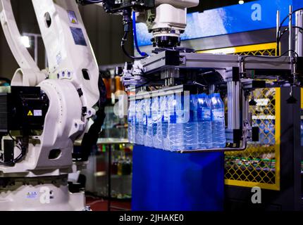 Il braccio del robot solleva il flacone di acqua nella linea di imbottigliamento dell'acqua. Foto Stock