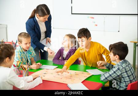 Insegnante e scolari felici giocare gioco da tavolo Foto Stock