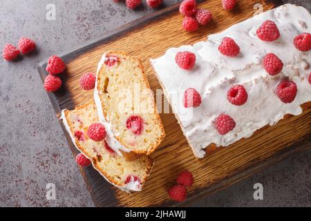 Delizioso pane per torte al lampone con glassa al limone da vicino su un asse di legno sul tavolo. Vista dall'alto orizzontale Foto Stock