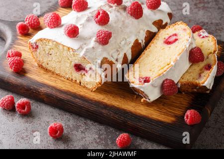 Delizioso pane per torte al lampone con glassa al limone da vicino su un asse di legno sul tavolo. Orizzontale Foto Stock