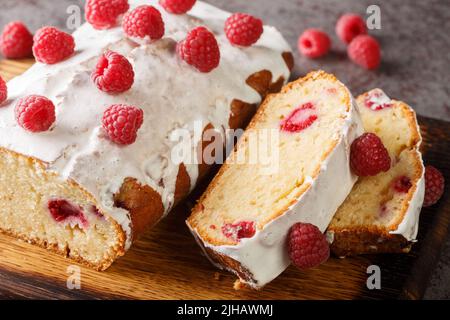 Torta di pane al lampone con glassa bianca da vicino su un asse di legno sul tavolo. Orizzontale Foto Stock