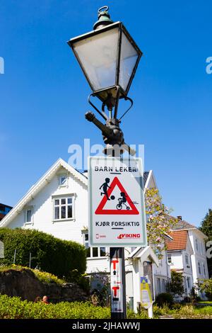 Attenzione ai bambini che giocano segno, tradizionale, bianco, legno dipinto case norvegesi su Øvre Strandgate, Stavanger, Norvegia. Foto Stock