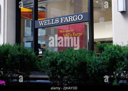 Wells Fargo branch front con logo prominente a New York. Logo Classic Wells Fargo su sfondo di cespugli verdi Foto Stock