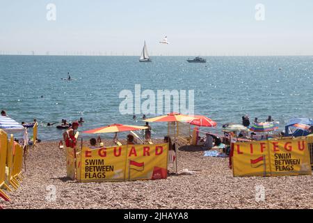 Brighton e Hove council Seafront sono in pieno swing sulla spiaggia mentre migliaia di persone si affollano alla spiaggia di ciottoli, sfruttando al massimo il caldo estremo. Sono in servizio ogni giorno dalle 10am alle 6pm o dalle 10:30am alle 5:30pm, a sostegno della squadra di mare del consiglio durante tutto l'anno. Foto Stock