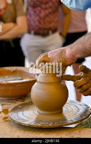 Rodi, Grecia - Maggio 2022: Potter usando le sue mani per modellare un nuovo vaso da argilla usando la ruota di un vasaio Foto Stock