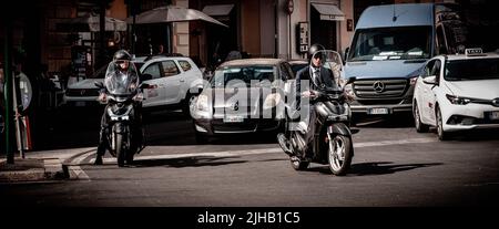 Roma, Italia - 6 giugno 2022: Uomo d'affari in moto attende di fronte al traffico sulla trafficata via Roma. Foto Stock