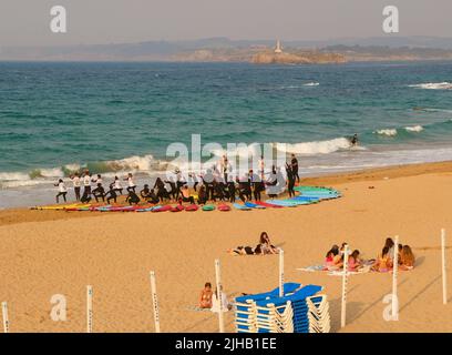 Un grande gruppo di surfisti in un semicerchio sulla spiaggia Sardinero Santander Cantabria Spagna in un semicerchio esercizi di riscaldamento durante una lezione Foto Stock