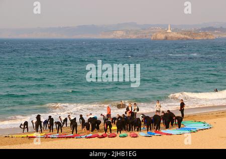 Un grande gruppo di surfisti in un semicerchio sulla spiaggia Sardinero Santander Cantabria Spagna in un semicerchio esercizi di riscaldamento durante una lezione Foto Stock