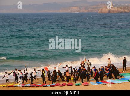 Un grande gruppo di surfisti in un semicerchio sulla spiaggia Sardinero Santander Cantabria Spagna in un semicerchio esercizi di riscaldamento durante una lezione Foto Stock