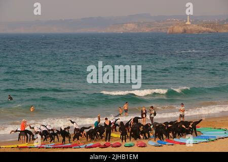 Un grande gruppo di surfisti in un semicerchio sulla spiaggia Sardinero Santander Cantabria Spagna in un semicerchio esercizi di riscaldamento durante una lezione Foto Stock