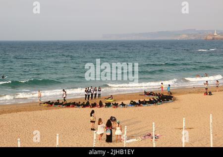 Un grande gruppo di surfisti in un semicerchio sulla spiaggia Sardinero Santander Cantabria Spagna in un semicerchio esercizi di riscaldamento durante una lezione Foto Stock