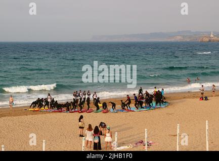 Un grande gruppo di surfisti in un semicerchio sulla spiaggia Sardinero Santander Cantabria Spagna in un semicerchio esercizi di riscaldamento durante una lezione Foto Stock