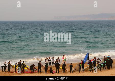 Un grande gruppo di surfisti in un semicerchio sulla spiaggia Sardinero Santander Cantabria Spagna in un semicerchio esercizi di riscaldamento durante una lezione Foto Stock