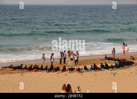 Un grande gruppo di surfisti in un semicerchio sulla spiaggia Sardinero Santander Cantabria Spagna in un semicerchio esercizi di riscaldamento durante una lezione Foto Stock