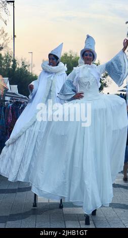 Due artisti del circo Bambolea si esibiscono in pubblico su palafitte e in costumi bianchi nei pressi di Piquio Santander Cantabria Spagna Foto Stock