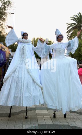 Due artisti del circo Bambolea si esibiscono in pubblico su palafitte e in costumi bianchi nei pressi di Piquio Santander Cantabria Spagna Foto Stock