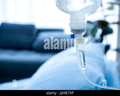 Primo piano della goccia di soluzione salina per infusione endovenosa del liquido di vitamina iv vicino al letto del paziente nella stanza dell'ospedale con spazio per la copia. Concetto sanitario e medico. Foto Stock