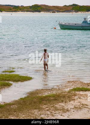 Una signora piuttosto giovane entra in mare a Port-Bail sur-Mer, Normandia, Francia, Europa Foto Stock