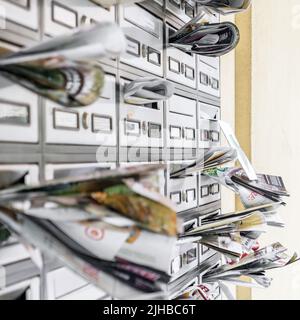 Caselle postali piene di volantini. Molti volantini pubblicitari sono appesi a una scatola di lettere sovraccaricata. Concetto di spam. Foto Stock