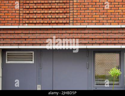 Elevazione di forma geometrica delle pareti esterne in mattoni con porte in metallo, edificio dal design moderno Foto Stock