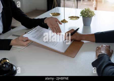 Il consulente legale presenta al client un contratto firmato con il martello e il diritto legale. Giustizia e avvocato concetto Foto Stock