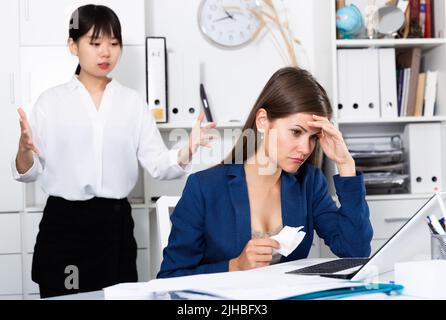 Il boss arrabbiato urlando per la giovane donna manager durante la lavorazione Foto Stock