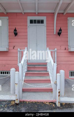 Vecchio edificio dipinto con vernice ad olio bianco e rosa, peeling alla vernice, lucchetti in ferro Foto Stock