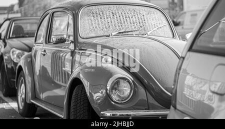 Un colpo panoramico bianco e nero di auto vecchia classica parcheggiata Volkswagen Beetle in strada Foto Stock