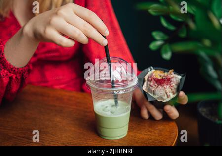 Primo piano torta di ghiaccio e cupcake in un caffè in mani femminili. Foto Stock