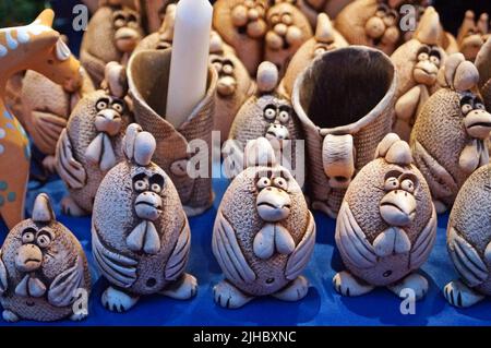 I gallo decorativi dell'argilla si levano in piedi su un contatore ad un mercato di Natale in un giorno di inverno Foto Stock