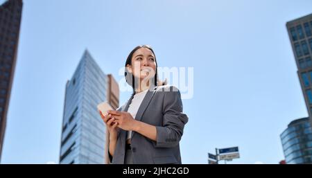 Giovane bella donna asiatica d'affari che usa lo smartphone sulla strada della città. Foto Stock