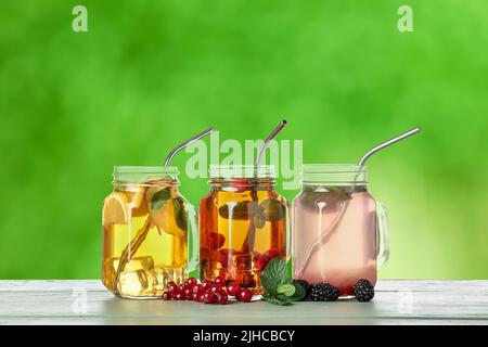 Vasetti Mason di diversi tè di frutta fredda al tavolo all'aperto Foto Stock