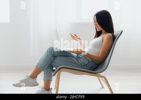 Confuso sconvolto abbronzato bella giovane donna asiatica scioccata da problemi di funzionamento con il portatile a casa soggiorno interno. Telecomando per comunicazioni a distanza Foto Stock